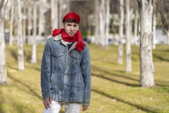 Young gay man wearing jean jacket and beret and red scarf outdoors