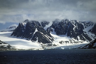 Snow-covered and glaciated rugged mountains surround the Magdalenefjord on Spitsbergen. Glaciers