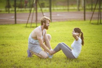 Sit ups fitness couple exercising sit up outside in graß Fit people working out cross training.