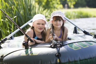 Little girls fishing on lake at summer