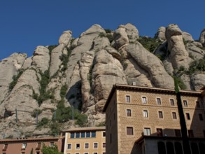 Building at the foot of rocky mountains under a clear sky in Montserrat, montserrat, spain