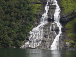 Close-up of a waterfall over green rocks with dense forest, Molde, Norway