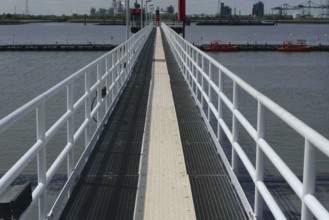 Metal walkway over the water, flanked by boats and an industrial backdrop, lillo, antwerp, belgium