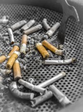 Smoked cigarettes butts in a dirty ashtray. Unhealthy life concept