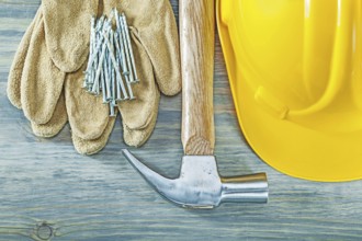 Hard hat protective gloves claw hammer nails on wooden board construction concept