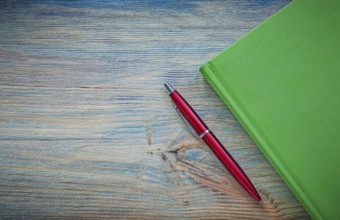 Green notepad pen on vintage wood board copy space education concept