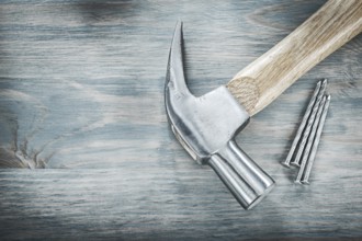 Claw hammer nails on vintage wooden board construction concept