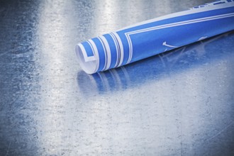 Roll of engineering drawings on metallic background construction concept