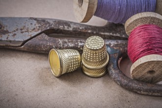 Reels of sewing threads thimbles scissors on vintage background