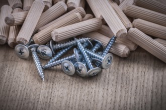 Woodworking dowels and construction nails on wood board top view