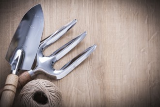 Stainless hand shovel trowel fork and hank of twine on vintage wooden board gardening concept
