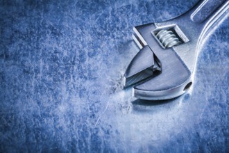 Copy space of stainless adjustable wrench on scratched metallic background construction concept