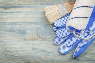Paint roller brushes protective gloves on wood board construction concept