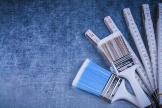 Wooden meter paintbrushes on scratched metallic background construction concept
