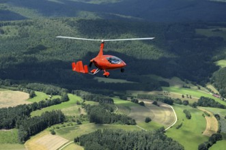 Gyrocopter in flight over woodland