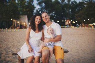 Theme of family summer holidays on the beach. Caucasian man and woman dad and mom hug a small baby