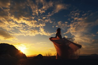 Bride in a fluttering dress stands on a mountain against the backdrop of a sunset sky.
