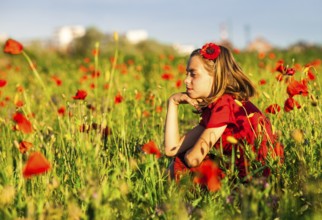Girl sit in the poppies field and enjoy the nature