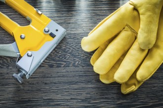 Pair of protective gloves construction stapler on wooden board