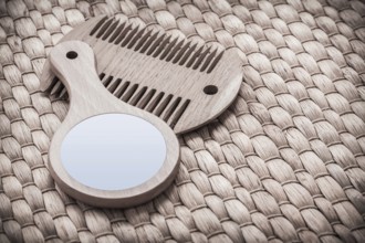 Wooden hand glass and comb on wicker mat healthcare concept