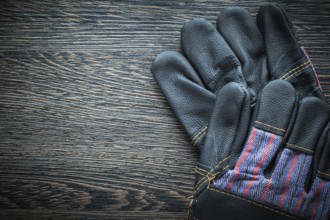 Pair of leather protective gloves on wooden board