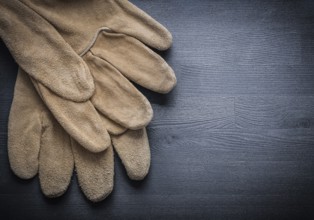 Two working leather gloves on dark wood board