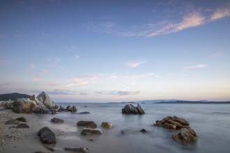View through rocks on a sandy beach into the sunset. Landscape shot with view to the horizon over