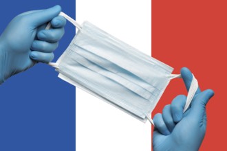 Doctor holding respiratory face mask in hands in blue gloves on background flag flag of France or