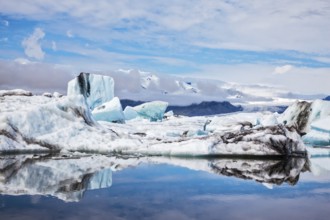 Icebergs and ice floes are reflected in the mirrored water of the ocean Bay. Ice lagoon in July.