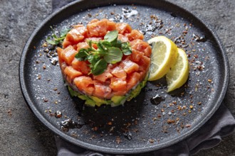 Food, Raw salmon, avocado purple onion salad served in culinary ring on black plate. Black concrete