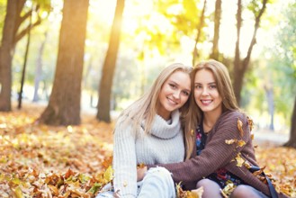 Fashionable beautiful young girlfriends walking together in the autumn park background. Having fun