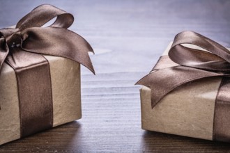 Two vintage pepr giftboxes with brown bows on old wooden board very close up view holiday concept