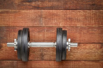 Heavy iron dumbbell on a rustic wood background - fitness concept