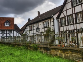Large half-timbered houses with a fenced garden and clouds in the sky, Herten, North
