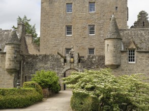 An old castle with stone walls, towers and an entrance surrounded by green plants, inverness,