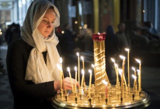 Woman lights the candle in russian orthodox church