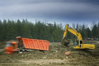 Preparation of the site for construction, leveling the soil. Excavator loads excess soil into