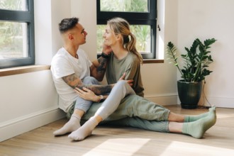 Junges, glückliches Paar in ihrer neuen Wohnung, das sich umarmt, während es bei einem Date auf dem