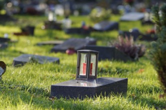Grave lantern on a gravestone of a cemetery with graves of the poor in front of a blurred
