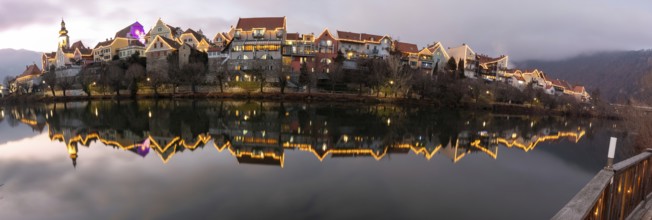 Christmas illuminated house facade of Frohnleiten reflected in the river Mur, panoramic view,