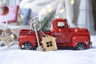 Red retro car with a Christmas tree decorates with the house key in the pickup truck for Christmas.