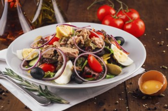 food still-life, Fresh nicoise salad with tuna, eggs, olives, and tomatoes on a wooden table with