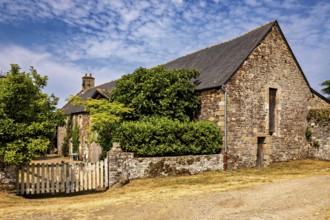 Rural stone house with a small wooden fence and green bushes under a clear sky, The Abbey de La