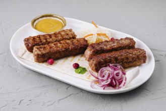 Food, Juicy grilled kebabs served on a white plate with fresh salad and dipping sauce