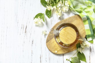 Therapeutic herbal tea. Hot Jasmine tea with jasmine flowers in a glass teapot on a rustic wooden