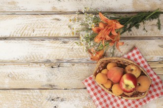 Summer berries and fruits on a wooden background with lilies and daisies, harvesting in the