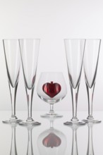 Different glasses and red heart on a glass plate