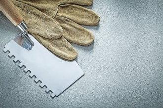 Paint scraper leather working gloves on concrete background construction concept
