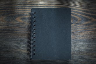 Black spiral notebook on vintage wooden board