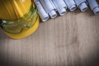 Safety spectacles rolled blueprints and hard hat construction concept